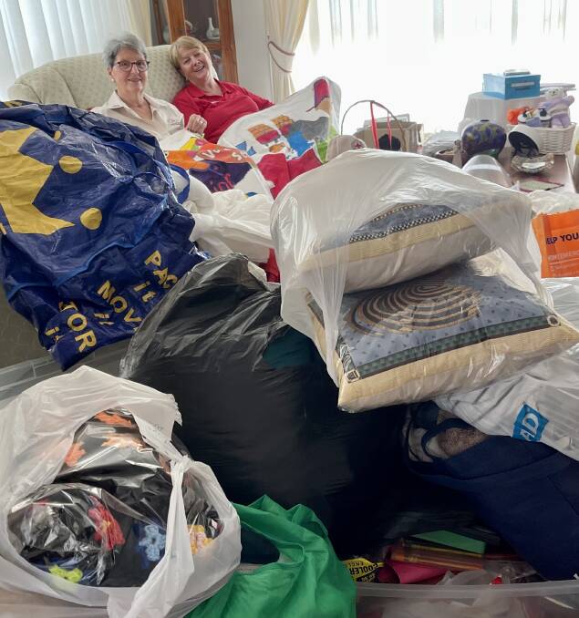 Kerrie Gray (right) and fellow Red Cross member Heather Smith in Kerries lounge room, surrounded by goods rescued from the flood-hit Lismore Red Cross shop.