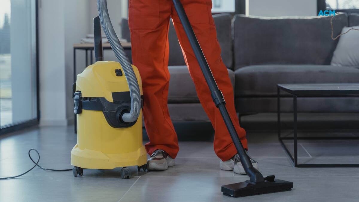 A cleaning worker uses an industrial vacuum. Picture via Canva